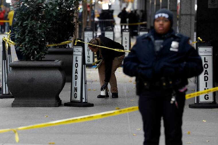 SHANNON STAPLETON / REUTERS
                                A member of the NYPD Crime Scene Unit works near evidence markers placed where shell casings were found at the scene where the CEO of UnitedHealthcare Brian Thompson was reportedly shot and killed in midtown Manhattan today