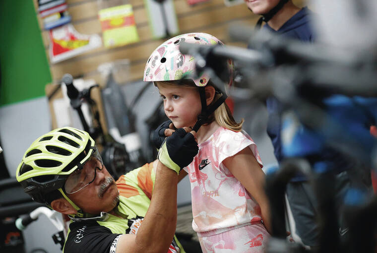 JAMM AQUINO / JAQUINO@STARADVERTISER.COM
                                Hawaii law states that anyone under the age of 16 must wear a helmet while riding a bike. Ivy Lown, 6, got fitted for a helmet Thursday by Mel Nakahata, general manager of The Bike Shop.