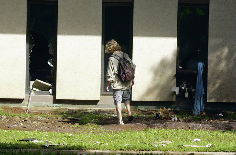 STAR-ADVERTISER / 2004
                                A student at UH Manoa wades through the muck to get a better look at the destroyed lower level of Hamilton Library on the campus. Students attending a night class in the room broke through windows in order to escape the rushing water.