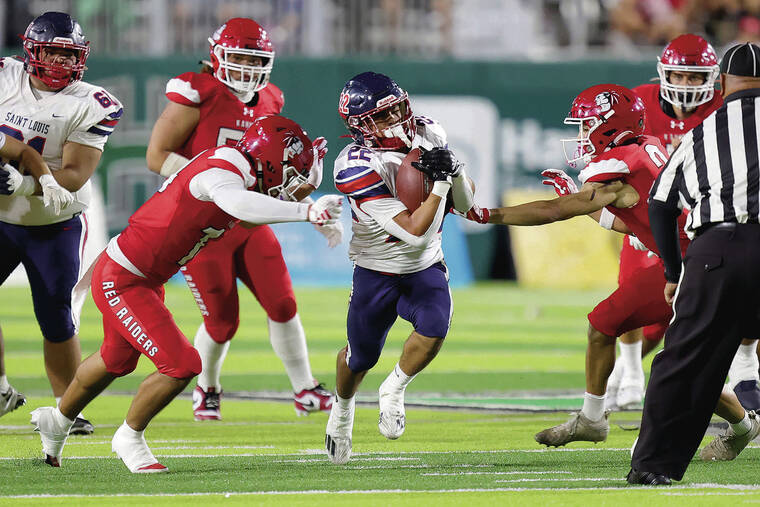 ANDREW LEE/ SPECIAL TO THE STAR-ADVERTISER
                                Saint Louis’ Charles-Titan Lacaden (22) rushes past Kahuku’s Aiden Manutai (14) and Kaimana Carvalho (2) with the ball during the HHSAA Open Division Football Championship Game on Friday at Clarence T.C. Ching Field in Honolulu.